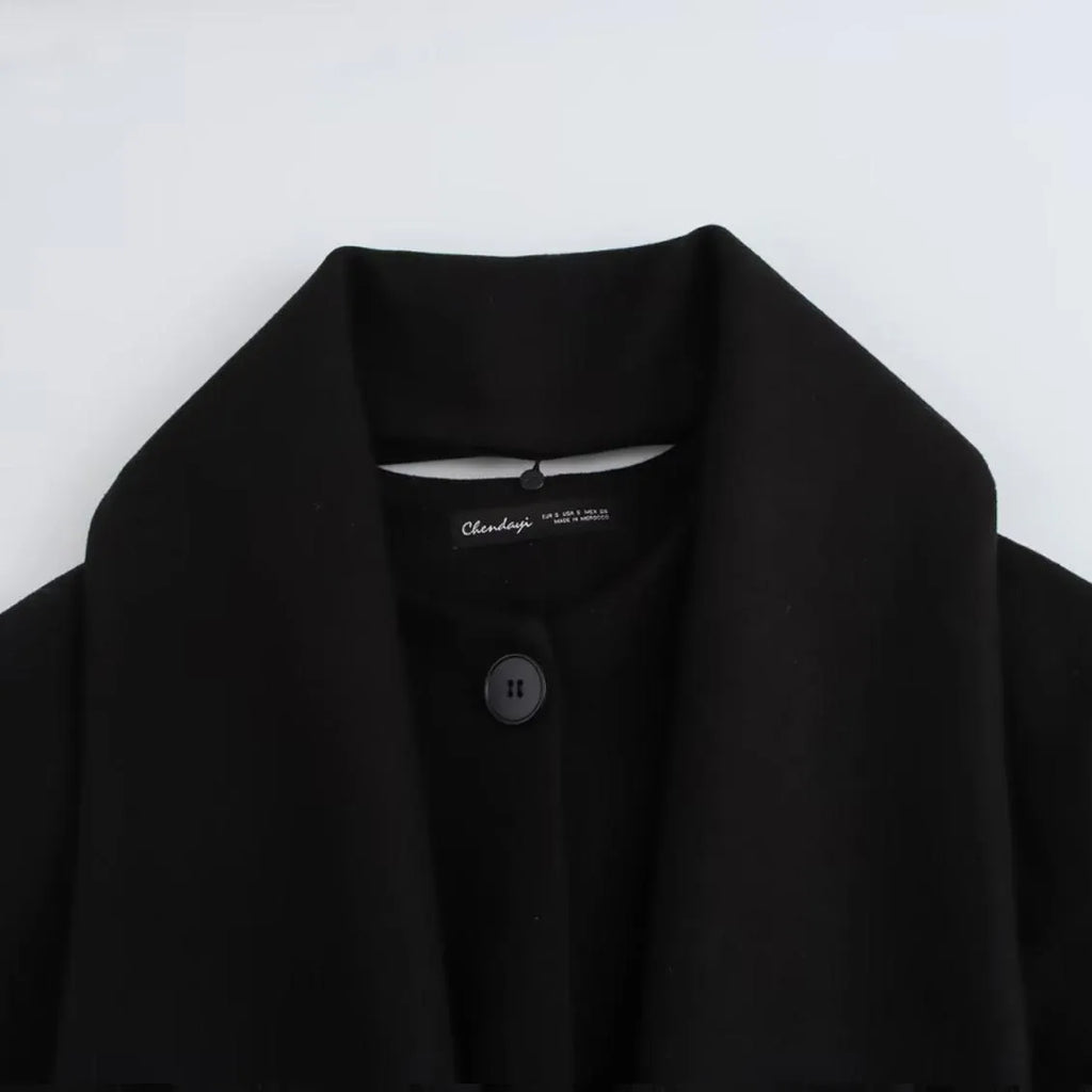 Women's long black polyester blend overcoat with a detachable artificial fur collar, showing pocket detail and street-fashion fit.