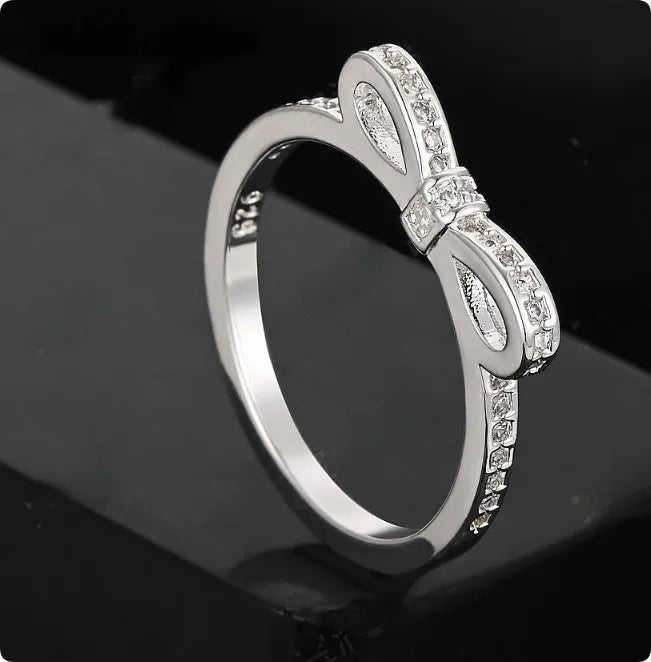 Silver couple style bow ring with rhinestone zircon crystals on finger showing electroplated finish