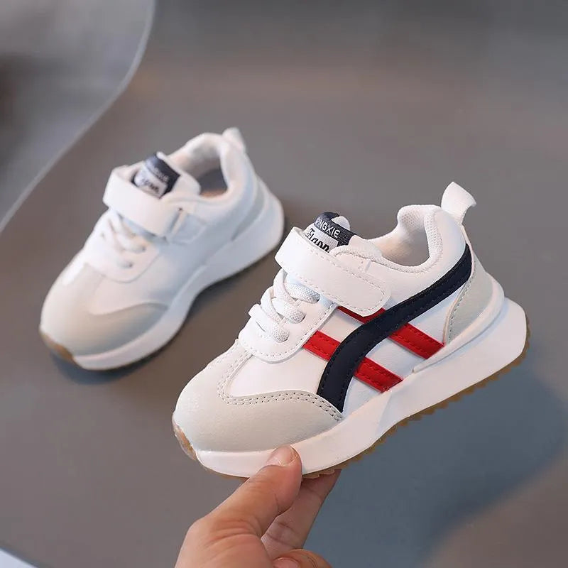 Children's white synthetic leather sneaker with Velcro strap and rubber sole.