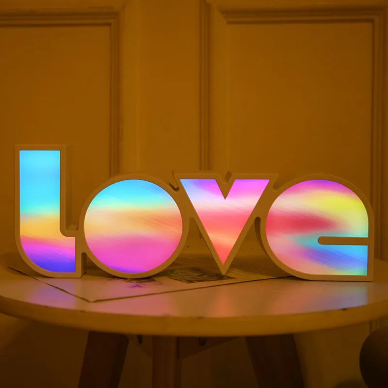 Rainbow-coloured plastic LED light spelling LOVE, standing 35.5cm tall on a table.