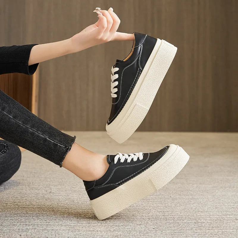 Black and white women's embossed leather platform sports shoes with a round toe and rubber sole.