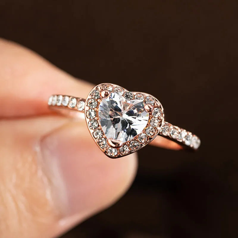Heart-shaped crystal wedding ring in rose gold or silvery finish on white background