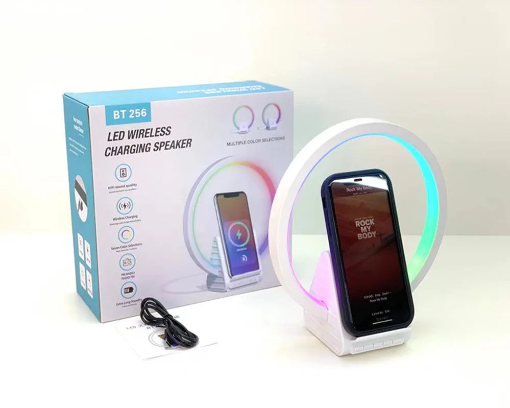 White smart Bluetooth speaker with ambient light and 15W wireless charging pad on desk