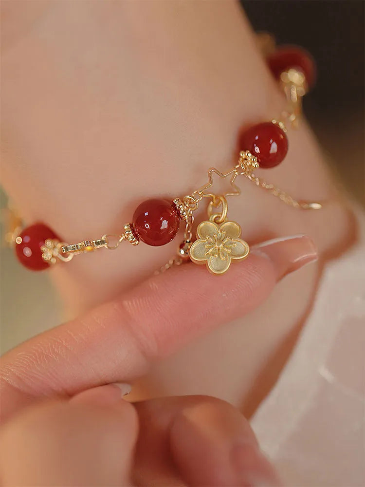 Close-up of a red agate double layer bracelet with floral and peach blossom detailing on a woman's wrist.