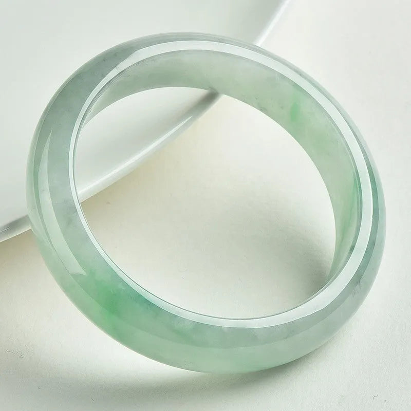 Natural light green jade bracelet on a wrist, showing unisex design and stone detail.