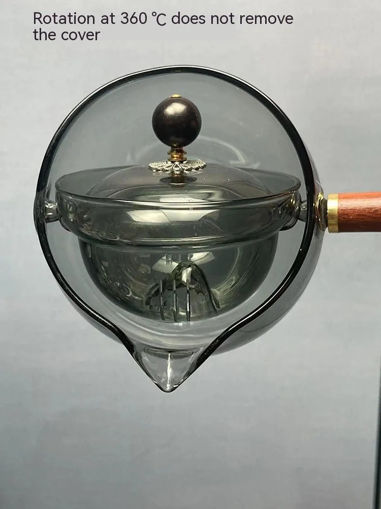 Semi-automatic rotary heat-resistant glass teapot with infuser and wooden handle on a table, transparent or grey