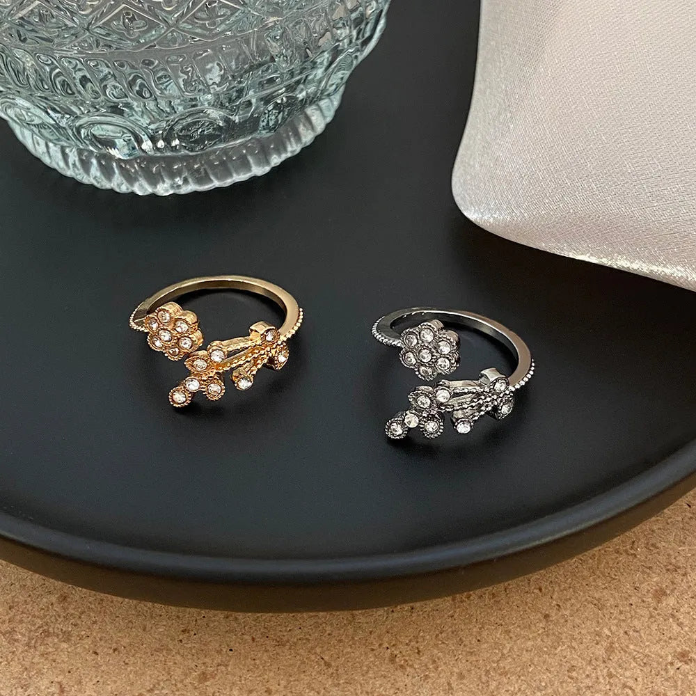 Women's open ring with flower and leaf design on a copper base with a diamond finish.