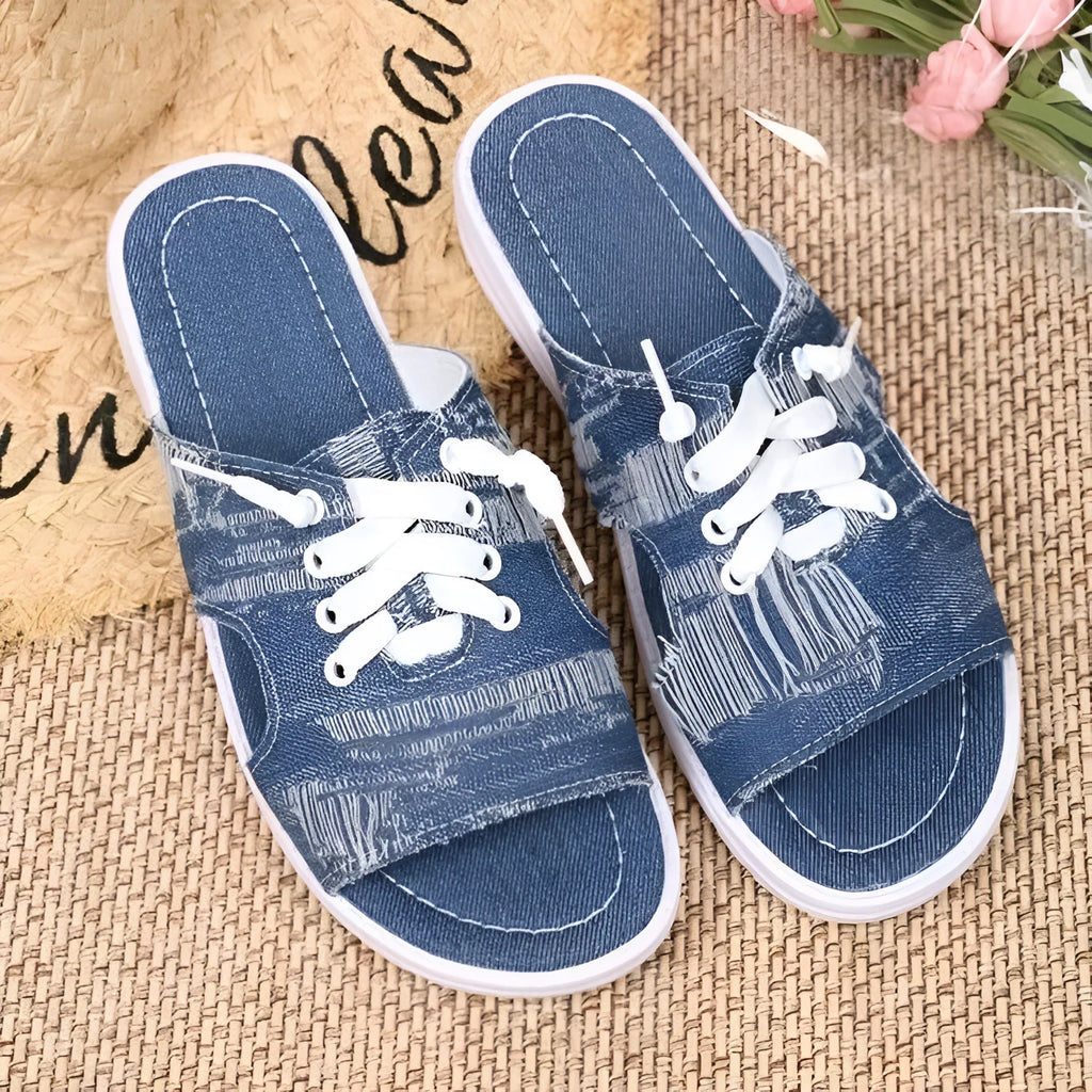 Blue women's Roman-style flat canvas slippers with a rubber sole, shown from the side.