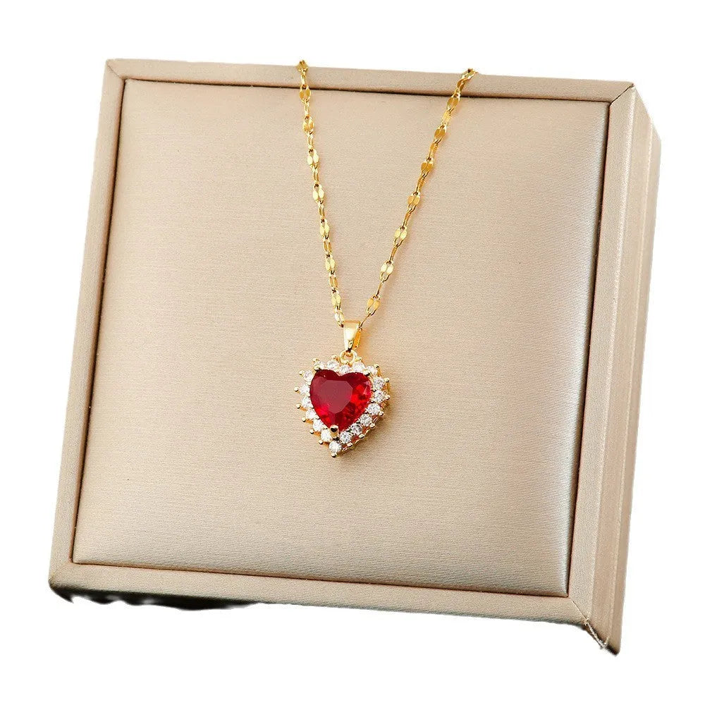 Gold red titanium steel jewellery set with heart and flower pendant necklace, matching stud earrings, and ring on a plain background.