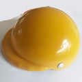 A small dog wearing a solid-colour plastic motorcycle cap helmet on its head.