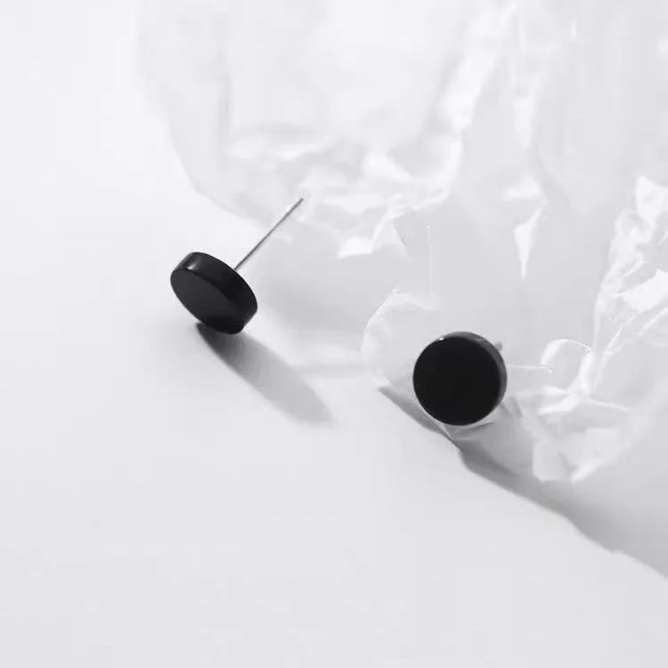 A pair of flat, round S999 sterling silver stud earrings on a plain background.