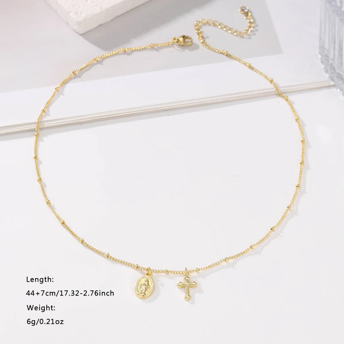 Gold-coloured copper necklace with a geometric cross pendant featuring a Virgin Mary centrepiece.