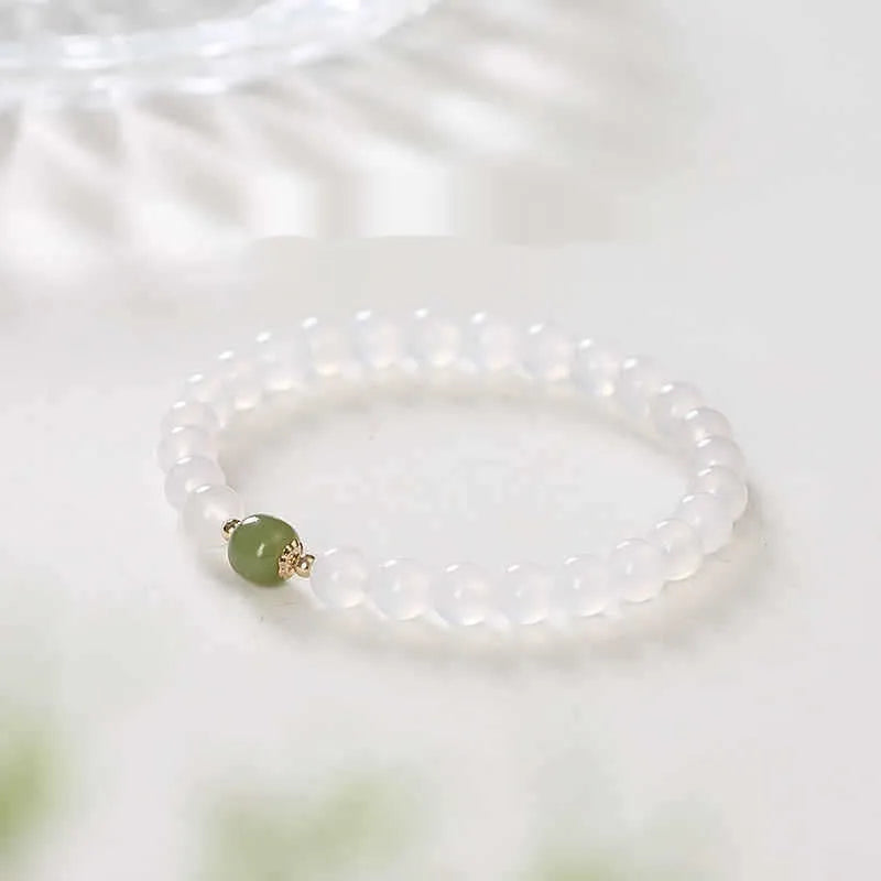 Handmade natural white agate crystal bracelet with cinnabar inlay on wrist, showing 8mm round beads.