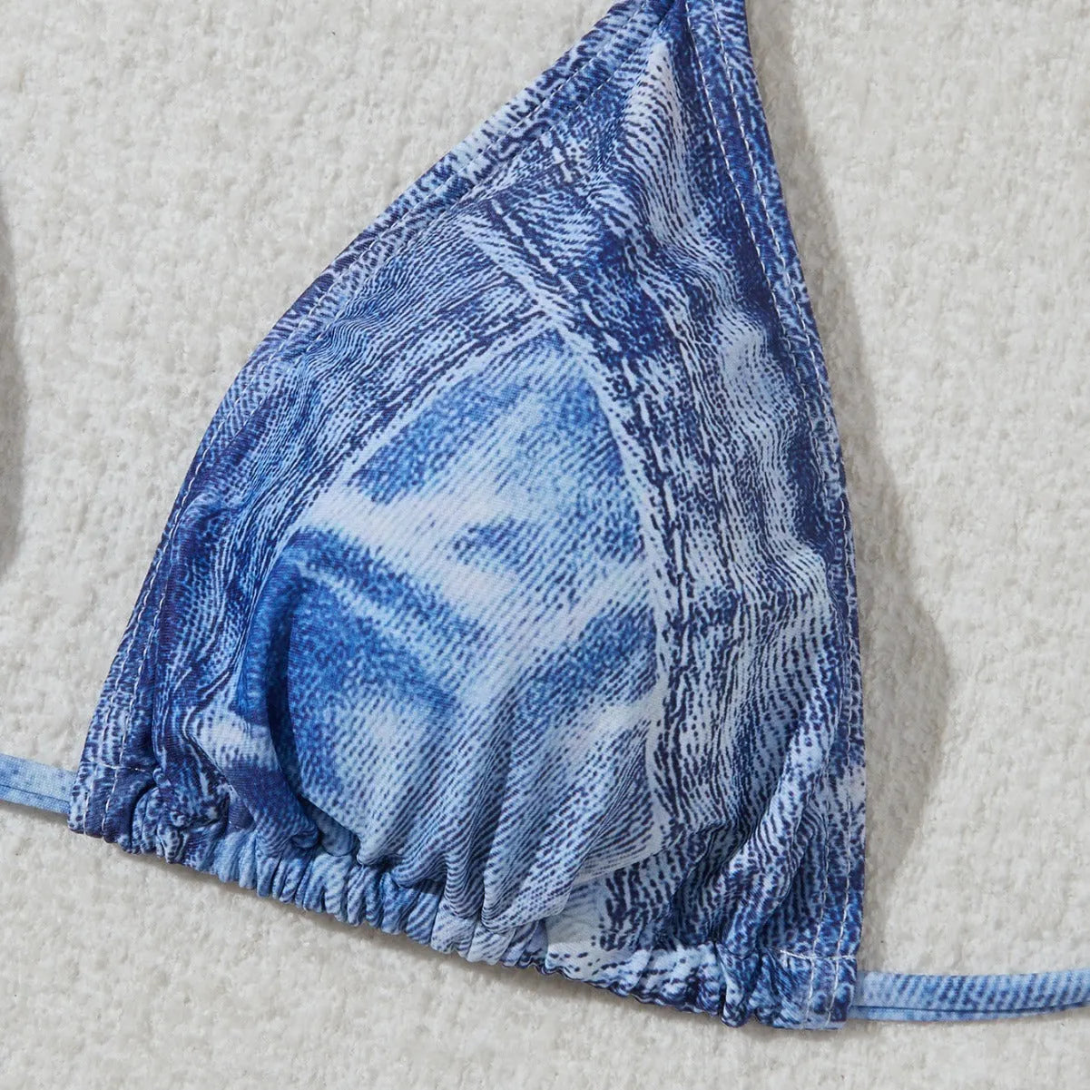 Women's denim blue printed bikini set with halterneck top and side-tie bottoms on a mannequin.