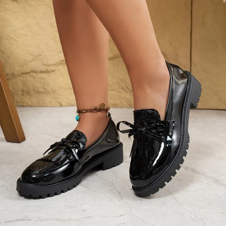 Women's brown and black loafers with a decorative bow on the front.