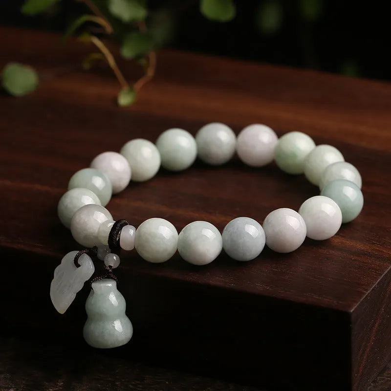 Apple green jade bracelet with carved Maitreya Buddha, gourd, and money bag beads.
