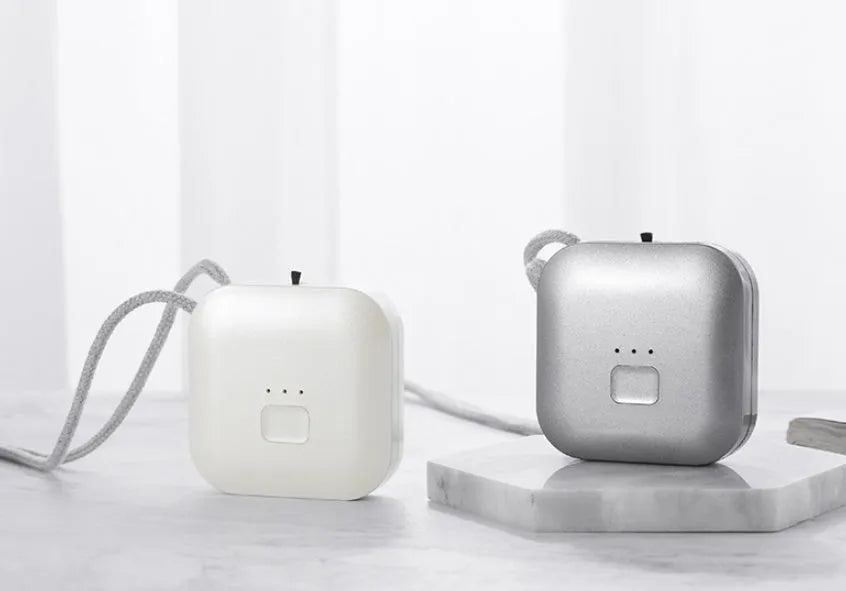 Mini USB air purifier pendant on a necklace, shown in pink colour with charging cable.