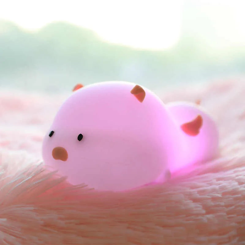 Cute pig silicone night light in Pink with sleeping face design on a wooden table