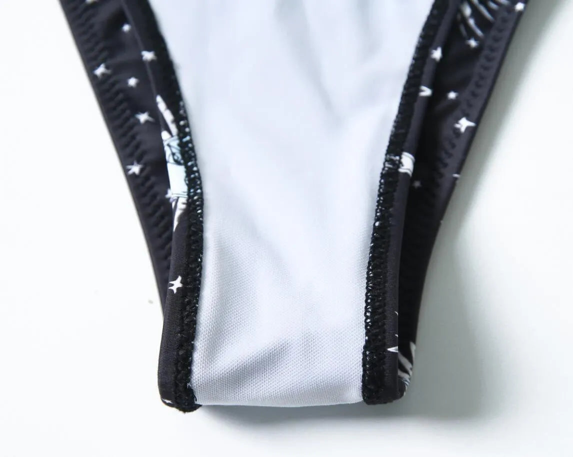 Black one-piece swimsuit with a bikini print pattern and a backless design.