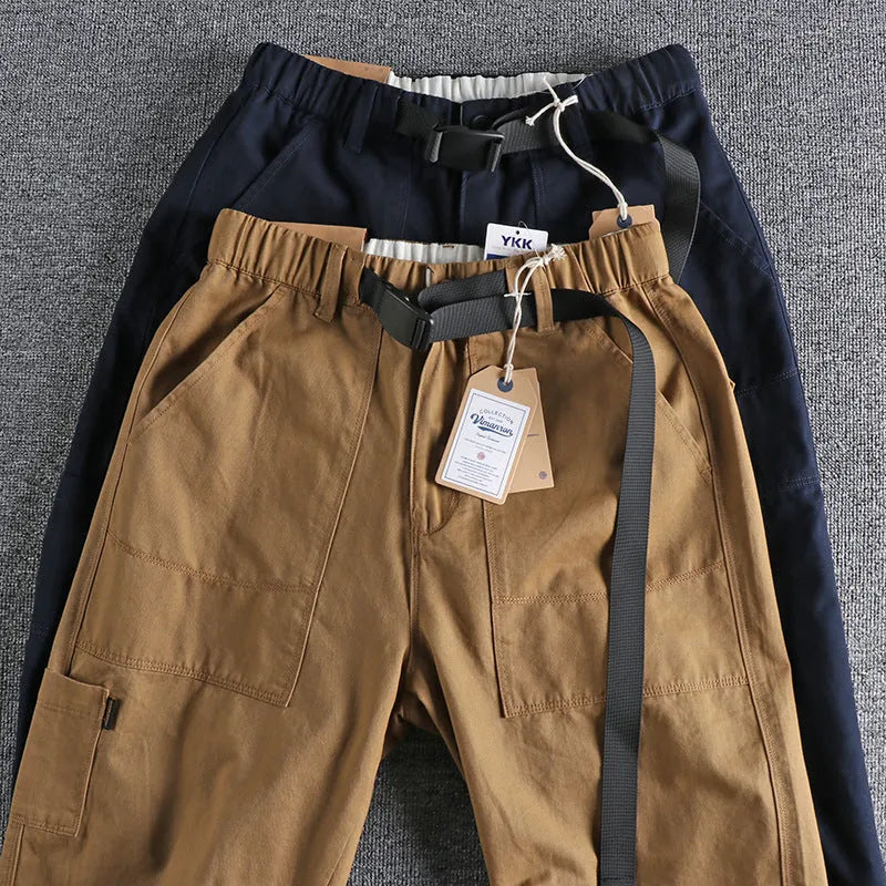 Men's khaki cotton work trousers with a matching N I buckle belt, showing three-dimensional cutting and a zipper fly.