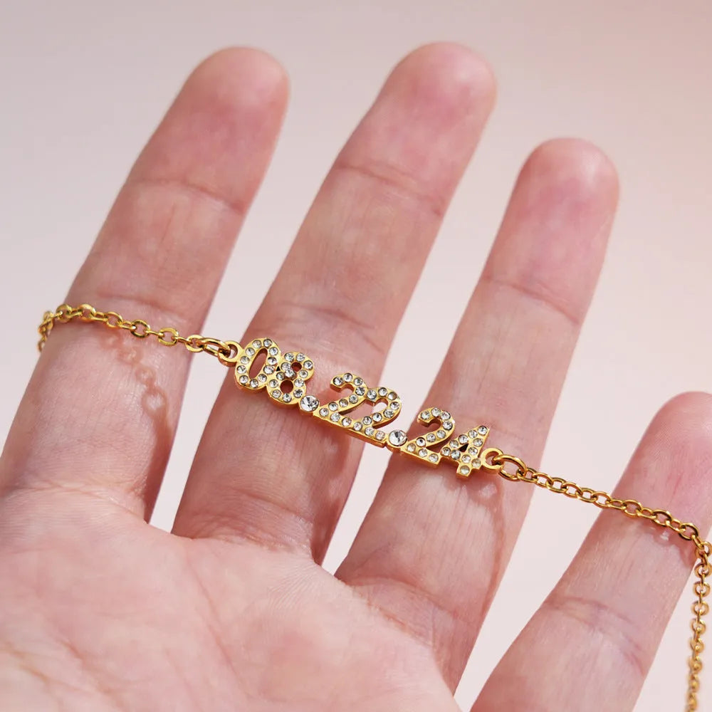 Stainless steel digital bracelet and necklace with diamond-set numbers in gold, rose gold, and steel finishes.