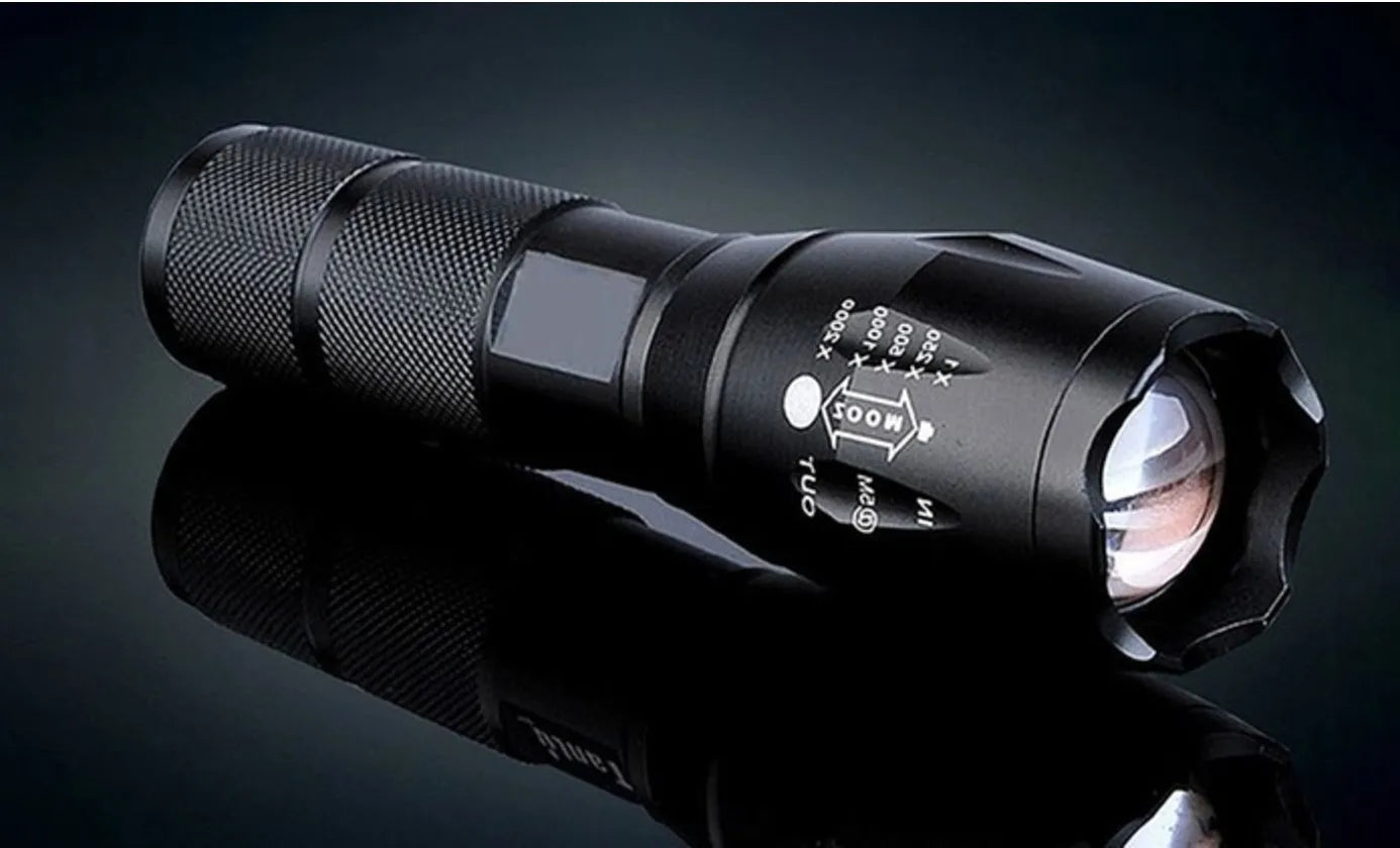 Black aluminium zoom flashlight showing adjustable head for focus, next to an 18650 battery.