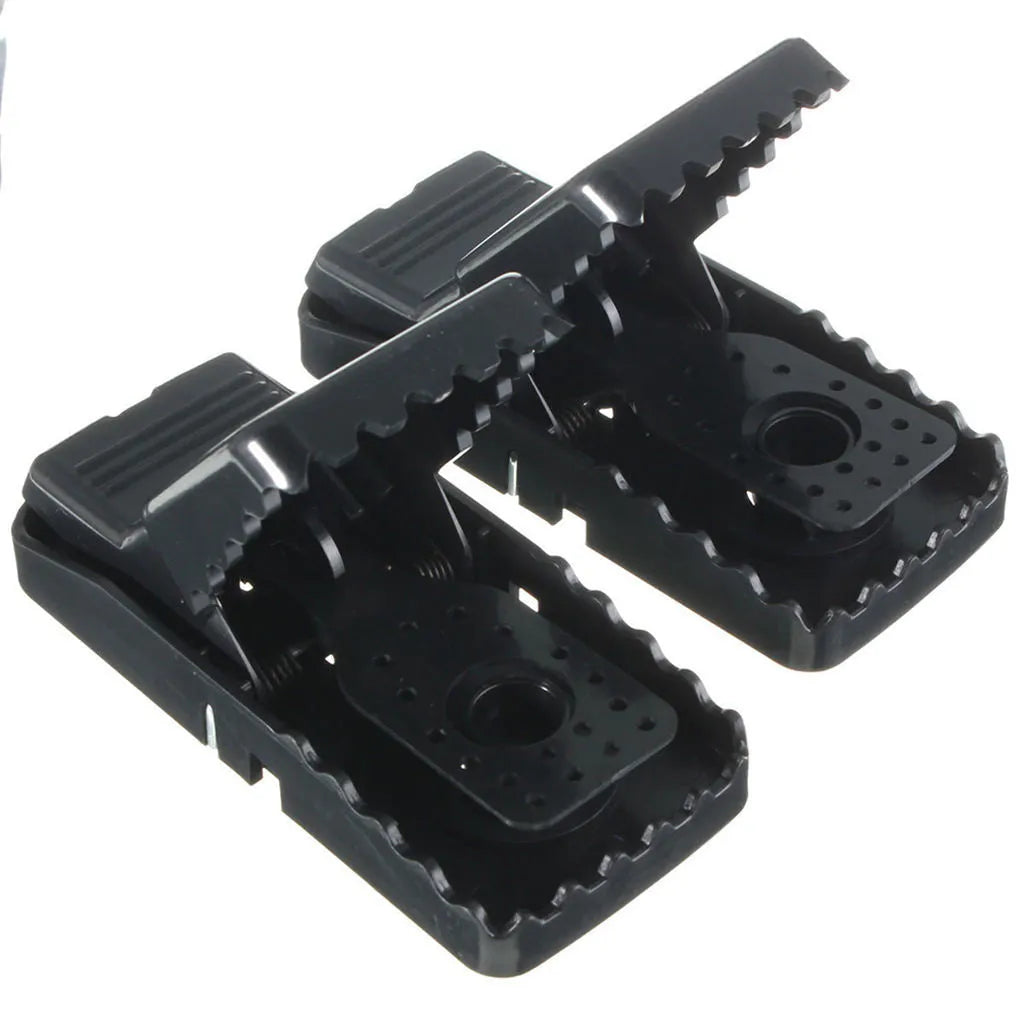 Six black plastic snapping mousetraps with set triggers on a white background.