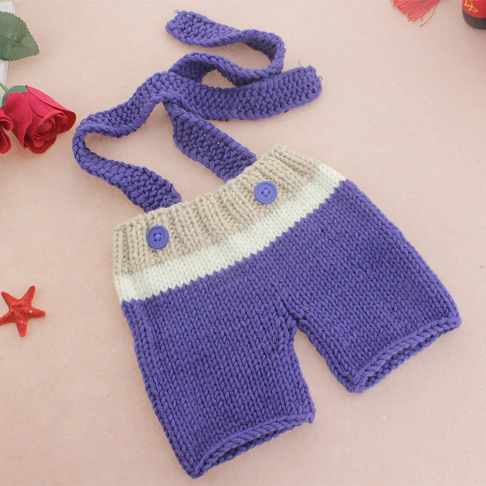 Handmade knitted wool baby photo suit in navy with hat and pants on a light background