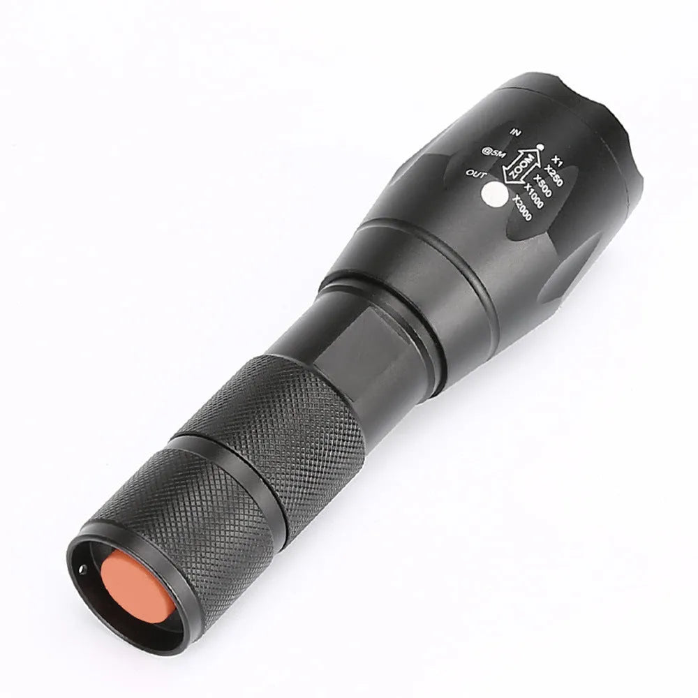 Black aluminium zoom flashlight showing adjustable head for focus, next to an 18650 battery.