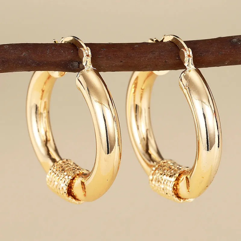 Golden geometric ear clip earrings with ring and line design elements made from copper