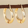 Golden geometric ear clip earrings with ring and line design elements made from copper