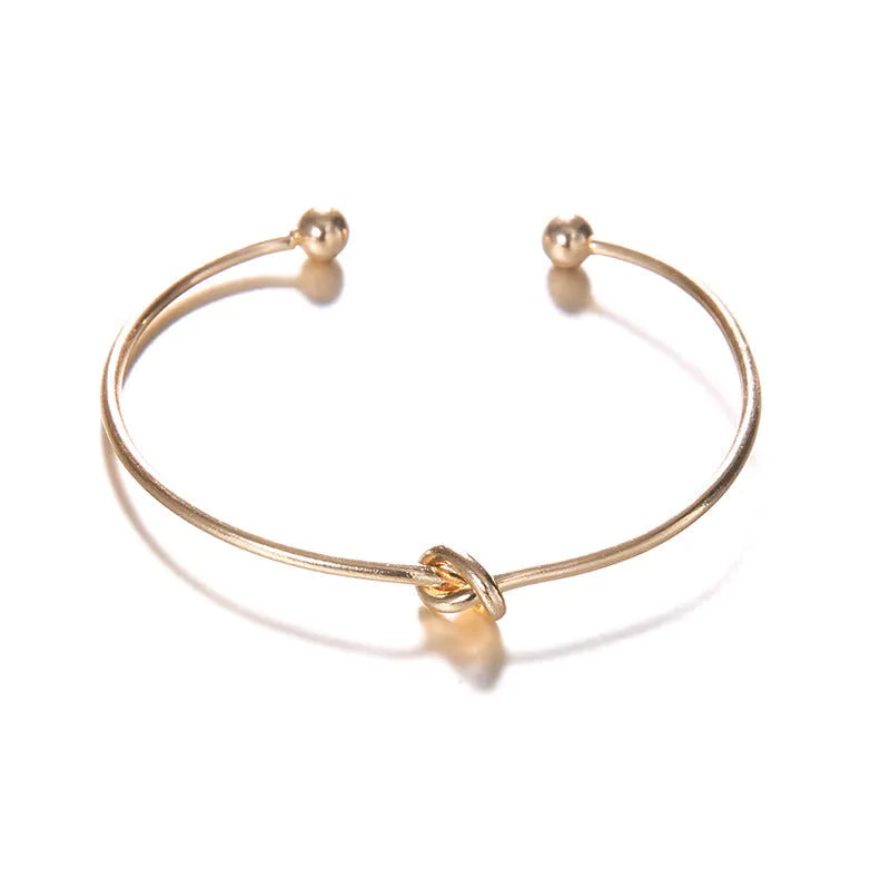 Gold electroplated alloy women's cuff bracelet with vintage arrow and knot design.