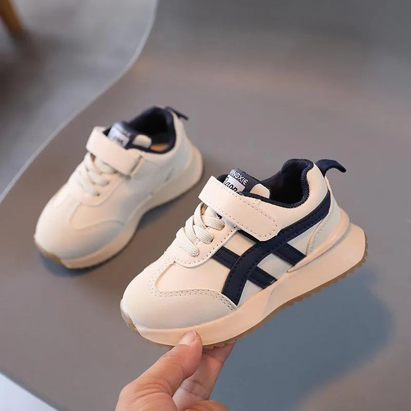 Children's white synthetic leather sneaker with Velcro strap and rubber sole.