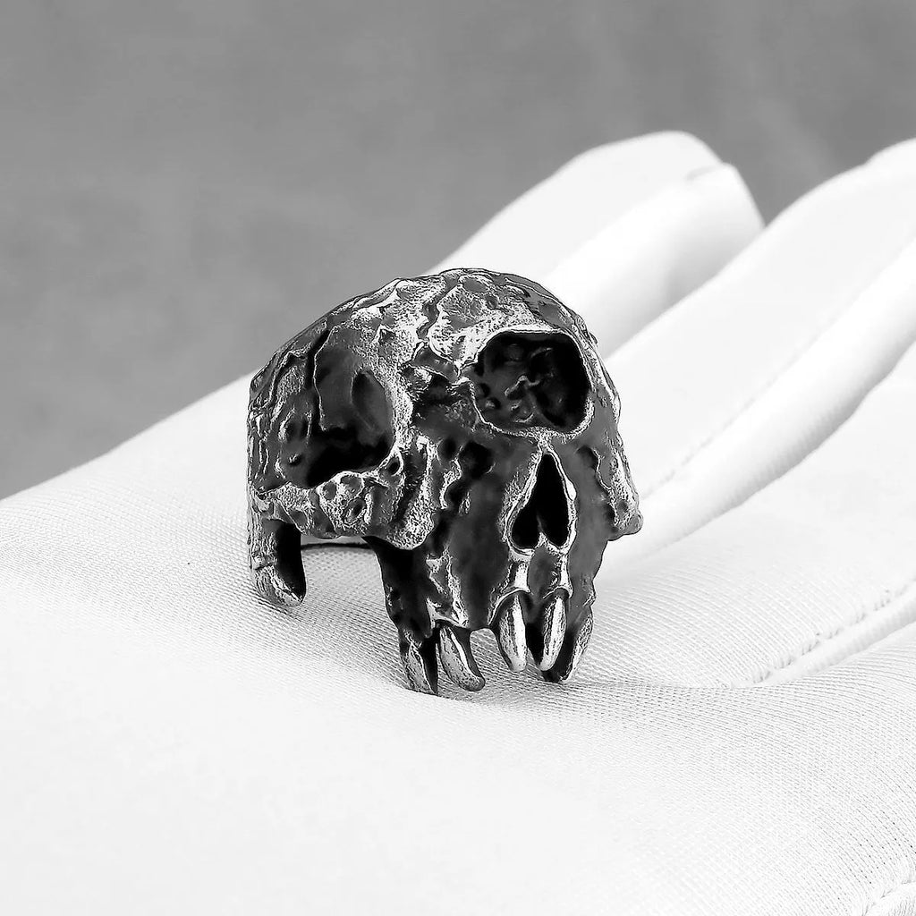 Close-up of a silver-toned alloy ring with a detailed one-eyed skull design on a black background.