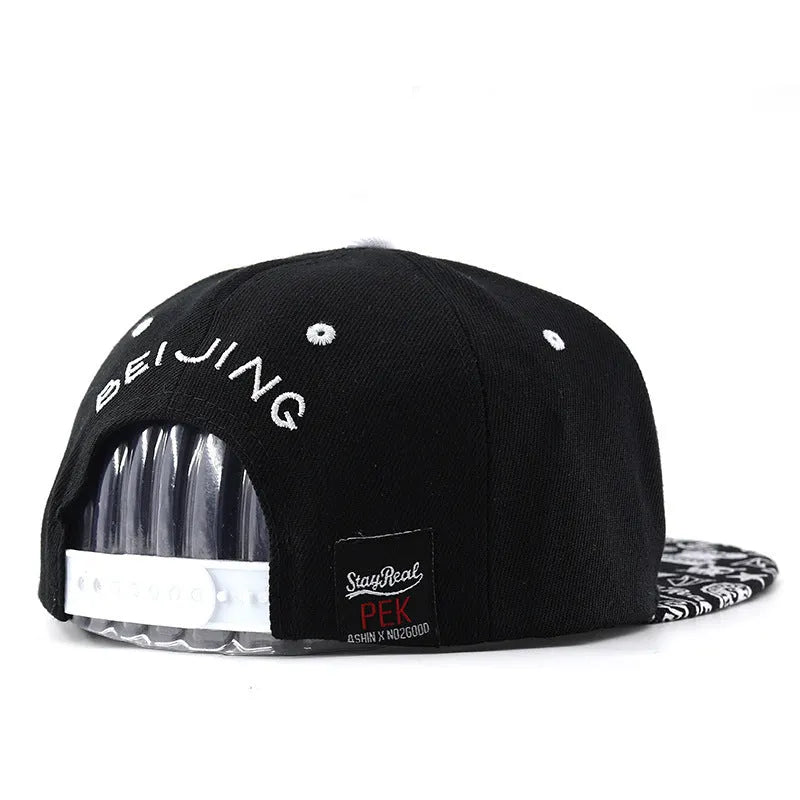 Black and white cotton baseball cap with letter embroidery on the front, showing adjustable strap.