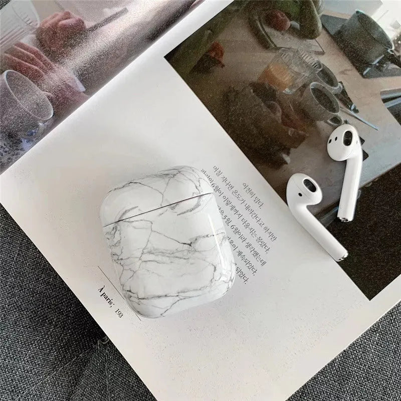 Hard white marble-pattern PC protective case fitted on an AirPods wireless earbud charging box.