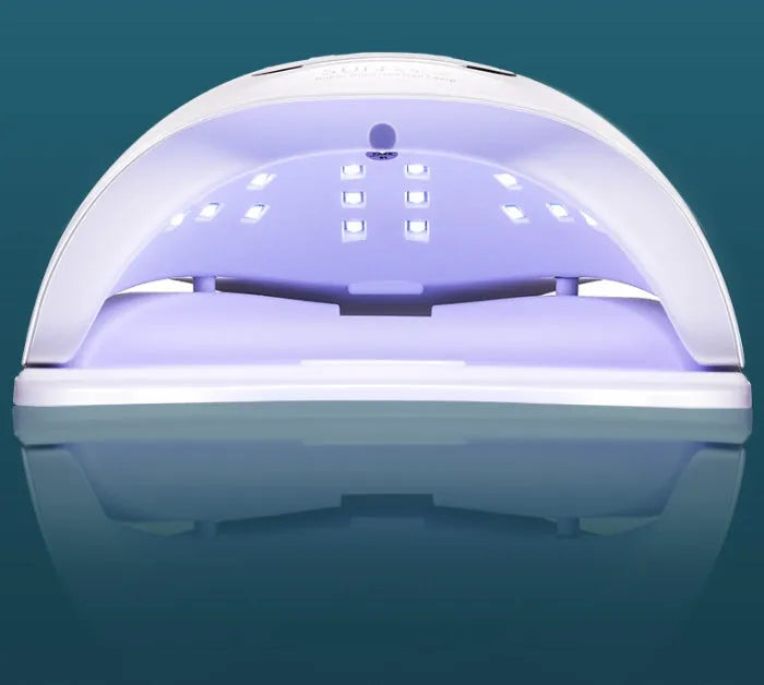 White nail polish quick-drying baking lamp dryer with dual UV and LED light sources on a clean surface.