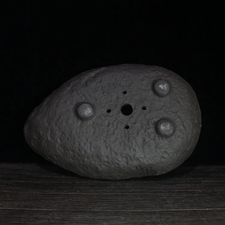Handmade purple clay flower pot with unique sculpted shape for floor-standing plants.