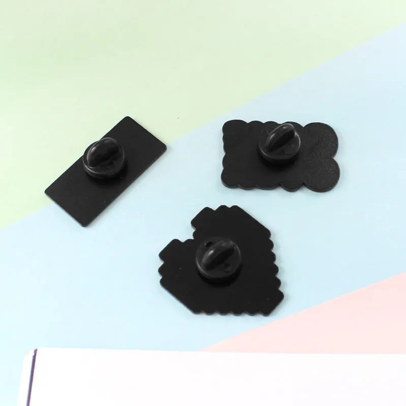 Stereo game console badge pin made from alloy metal on a bag, showing three colour variant options.