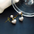 Close-up of women's heart-shaped alloy stud earrings with pearl-like appearance and electroplated finish.