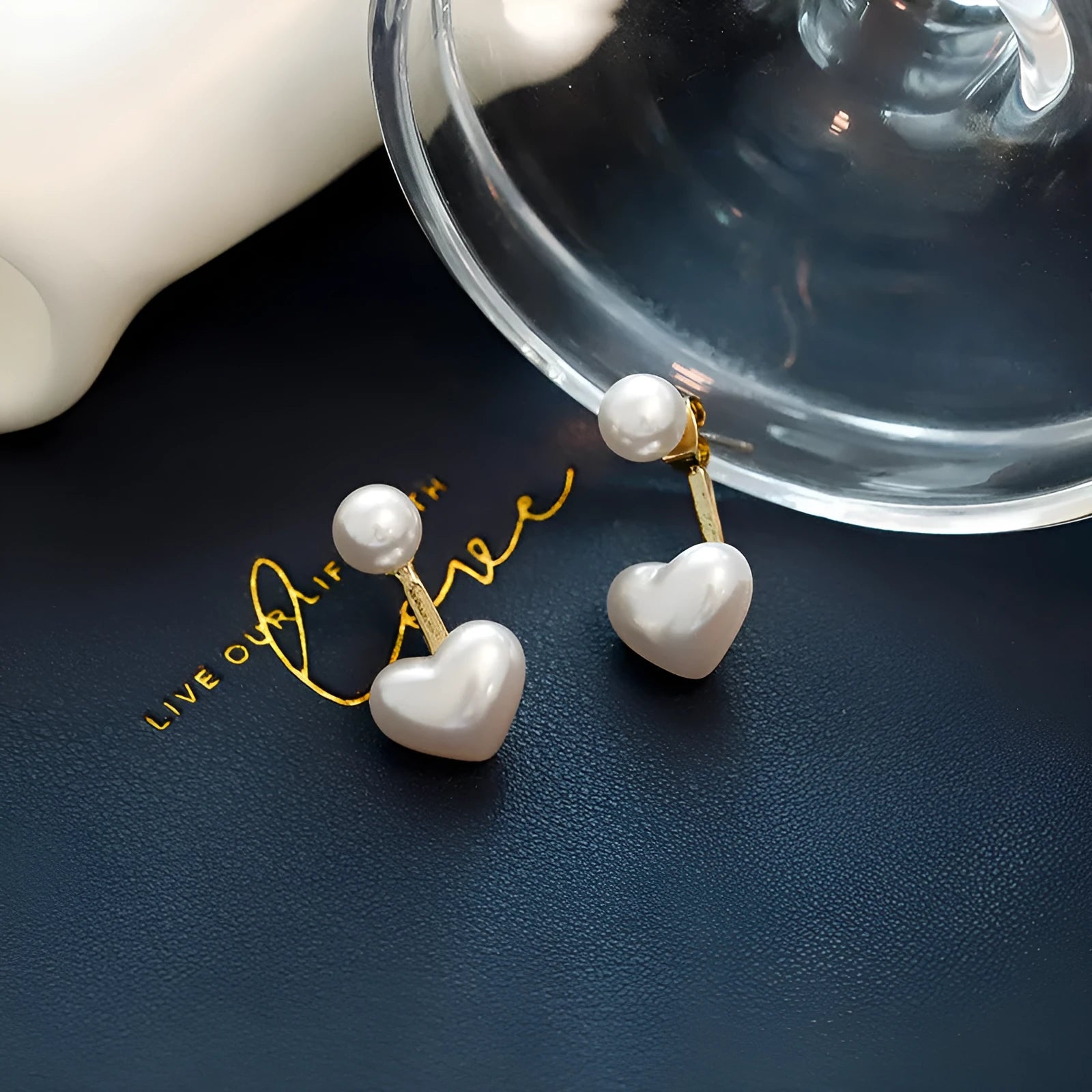 Close-up of women's heart-shaped alloy stud earrings with pearl-like appearance and electroplated finish.