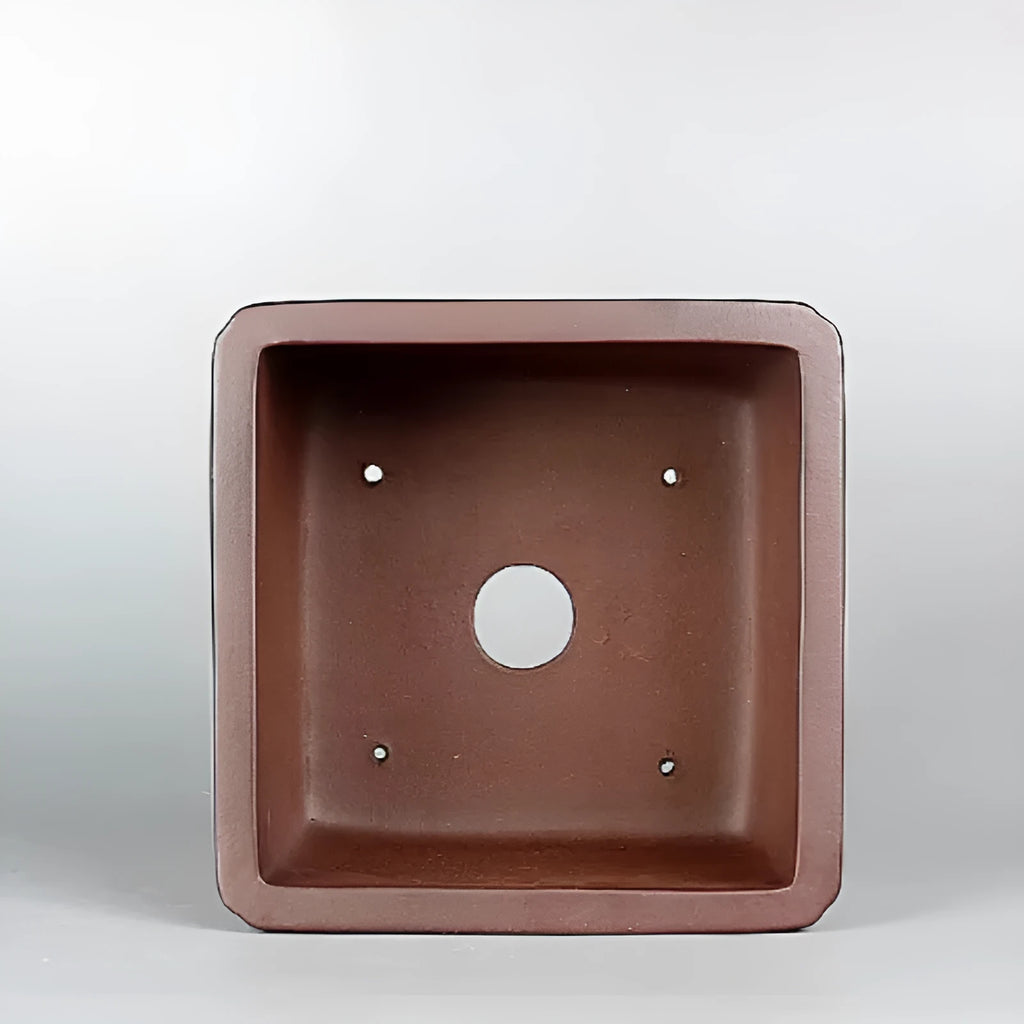 Handmade antique brown purple clay flower pot with classical design on a desktop.