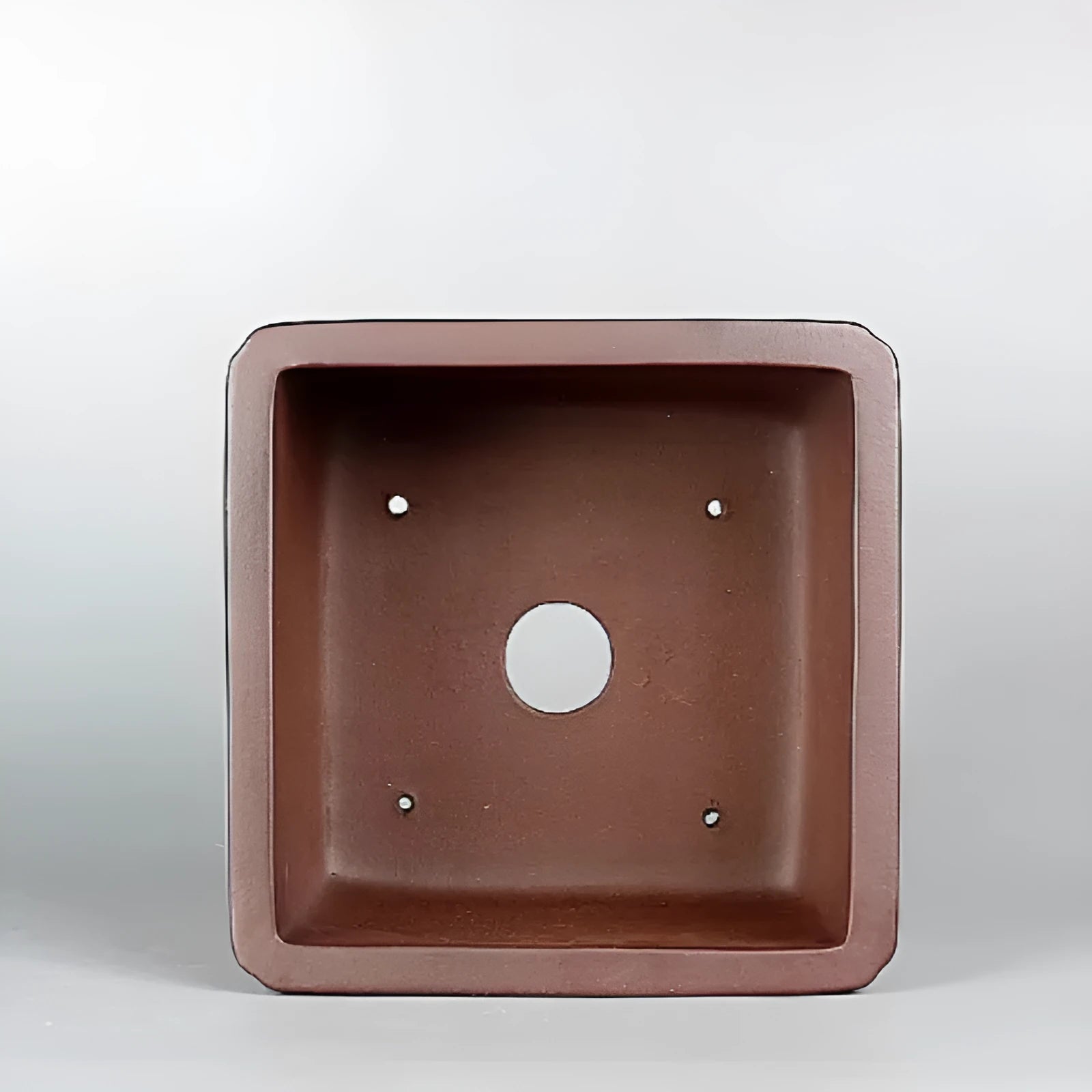 Handmade antique brown purple clay flower pot with classical design on a desktop.