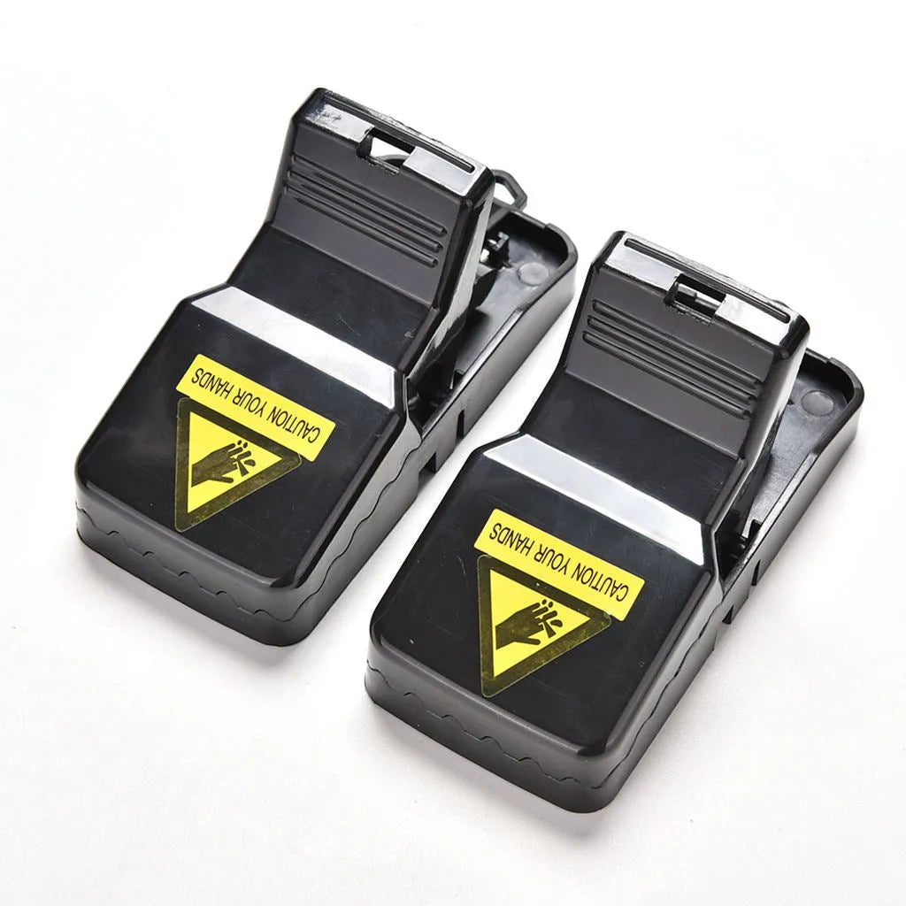 Six black plastic snapping mousetraps with set triggers on a white background.