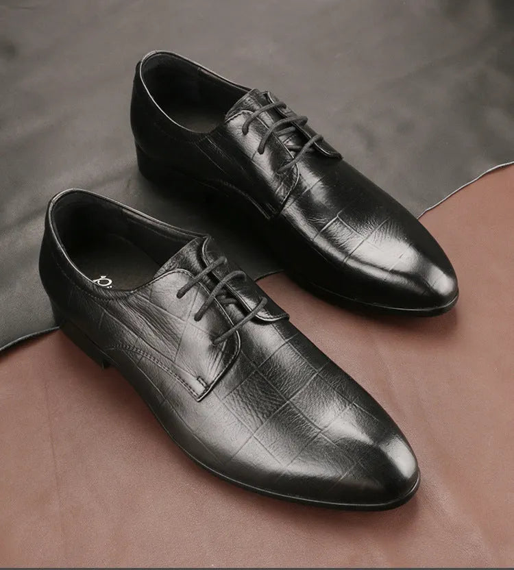 Men's black leather derby shoes with a pointed toe and rubber sole on a neutral background.