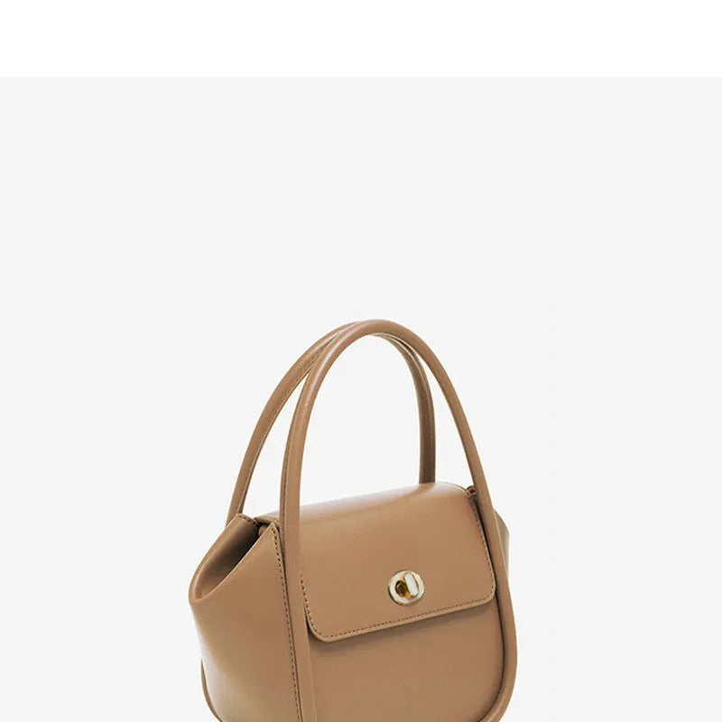 A wing-shaped cow leather tote bag with a buckle latch closure, shown in blue with a single cross-body strap.