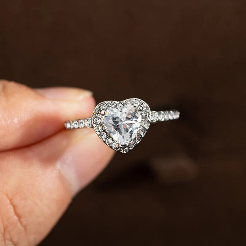 Heart-shaped crystal wedding ring in rose gold or silvery finish on white background