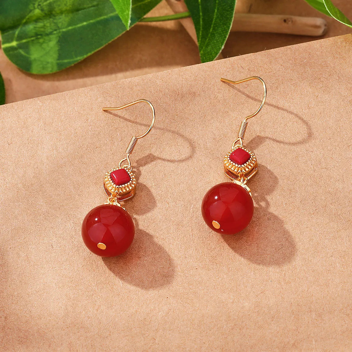 Round red agate bead drop earrings with silver-inlaid jasper accents on a geometric copper alloy hook.