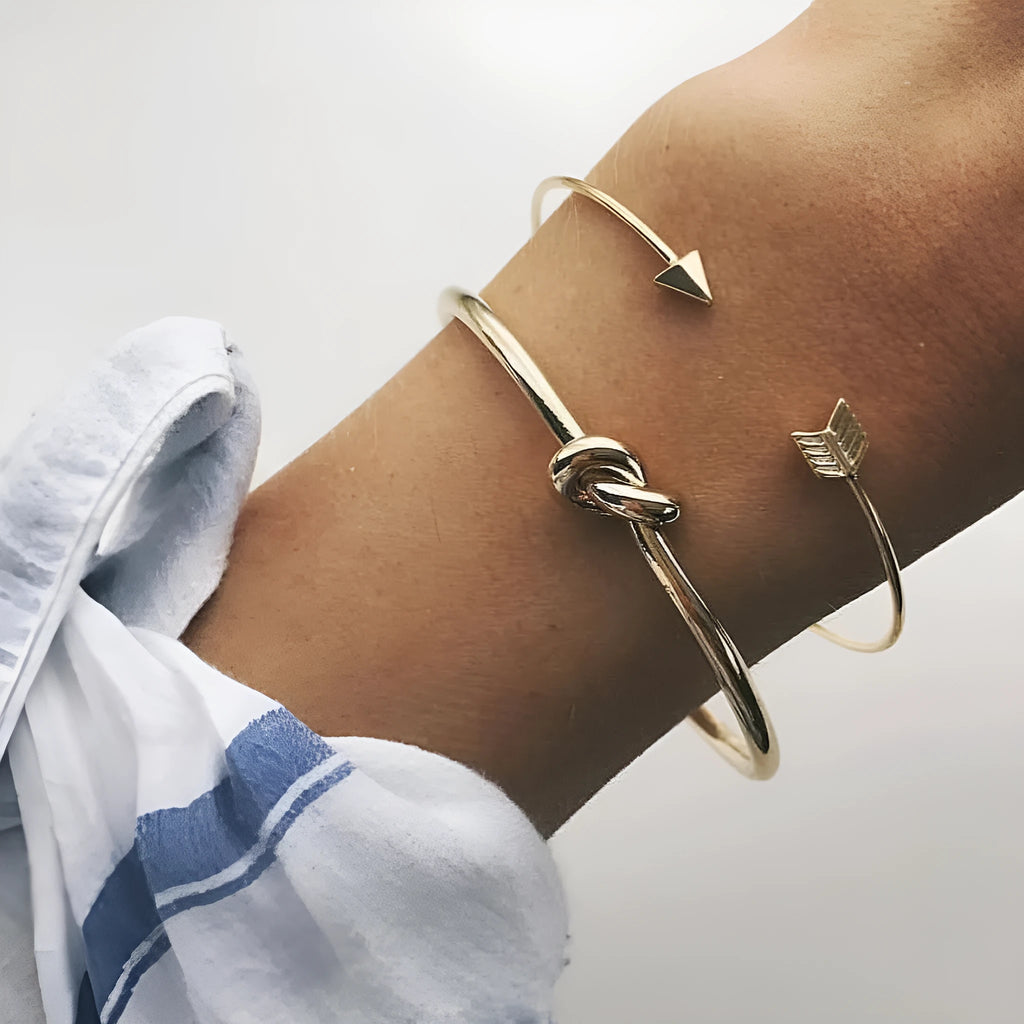 Gold electroplated alloy women's cuff bracelet with vintage arrow and knot design.