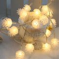 Warm white battery-powered LED pine cone lights on a string for festive decoration.